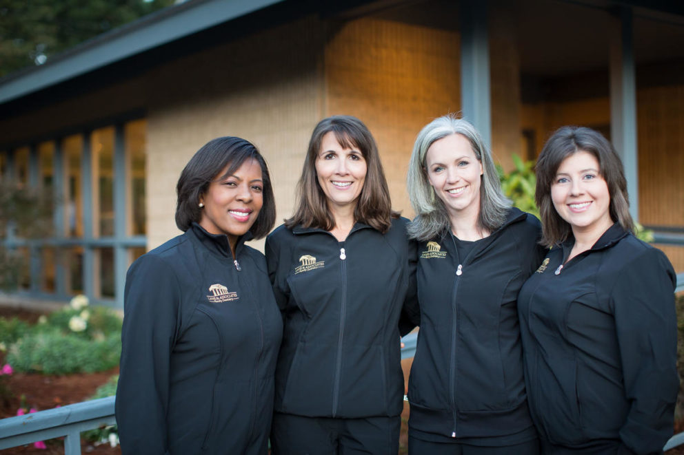 Group of four Lane & Associates Employees with arms around each other in black scrubs