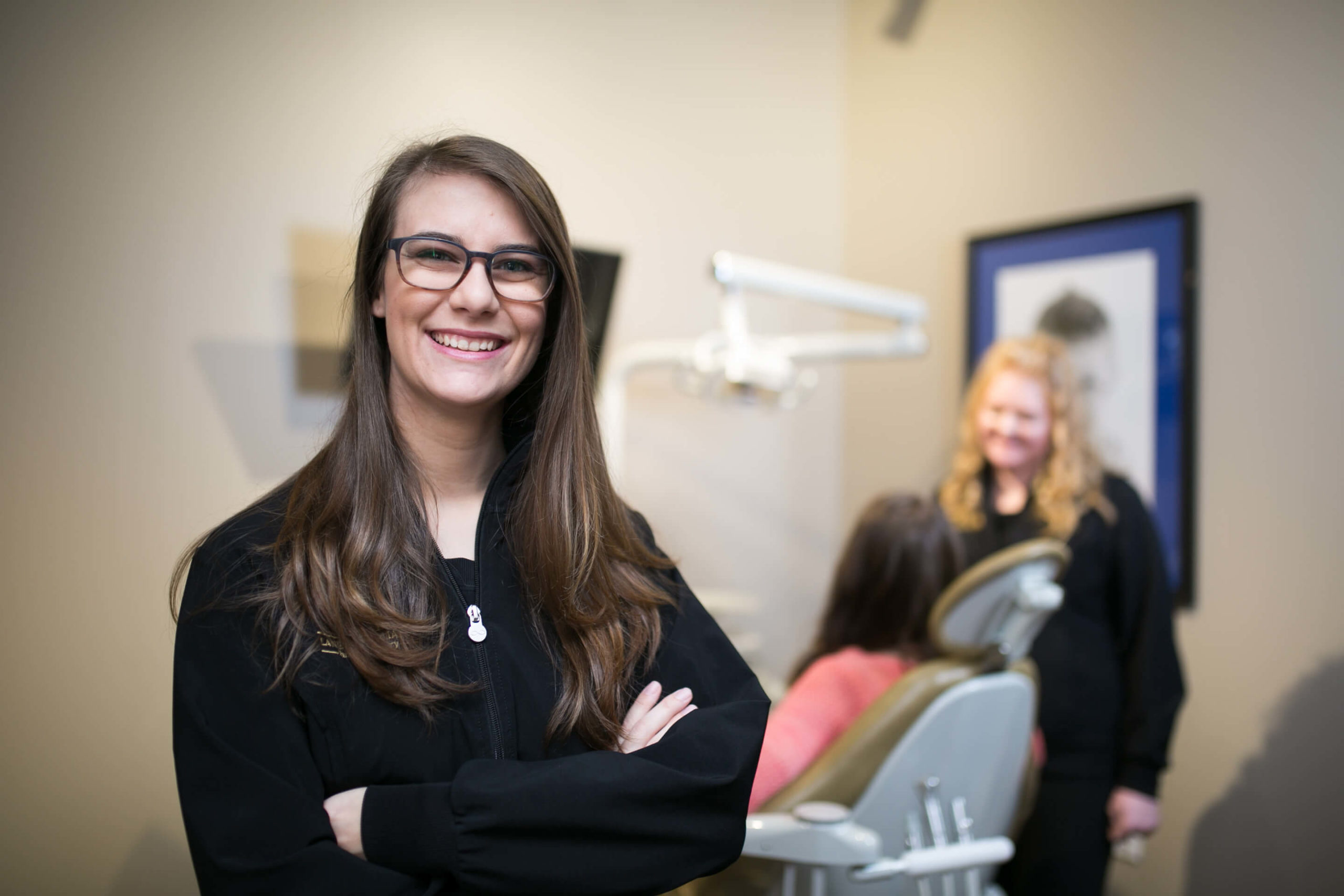Dental Treatment Coordinator smiling with patient in chair in background