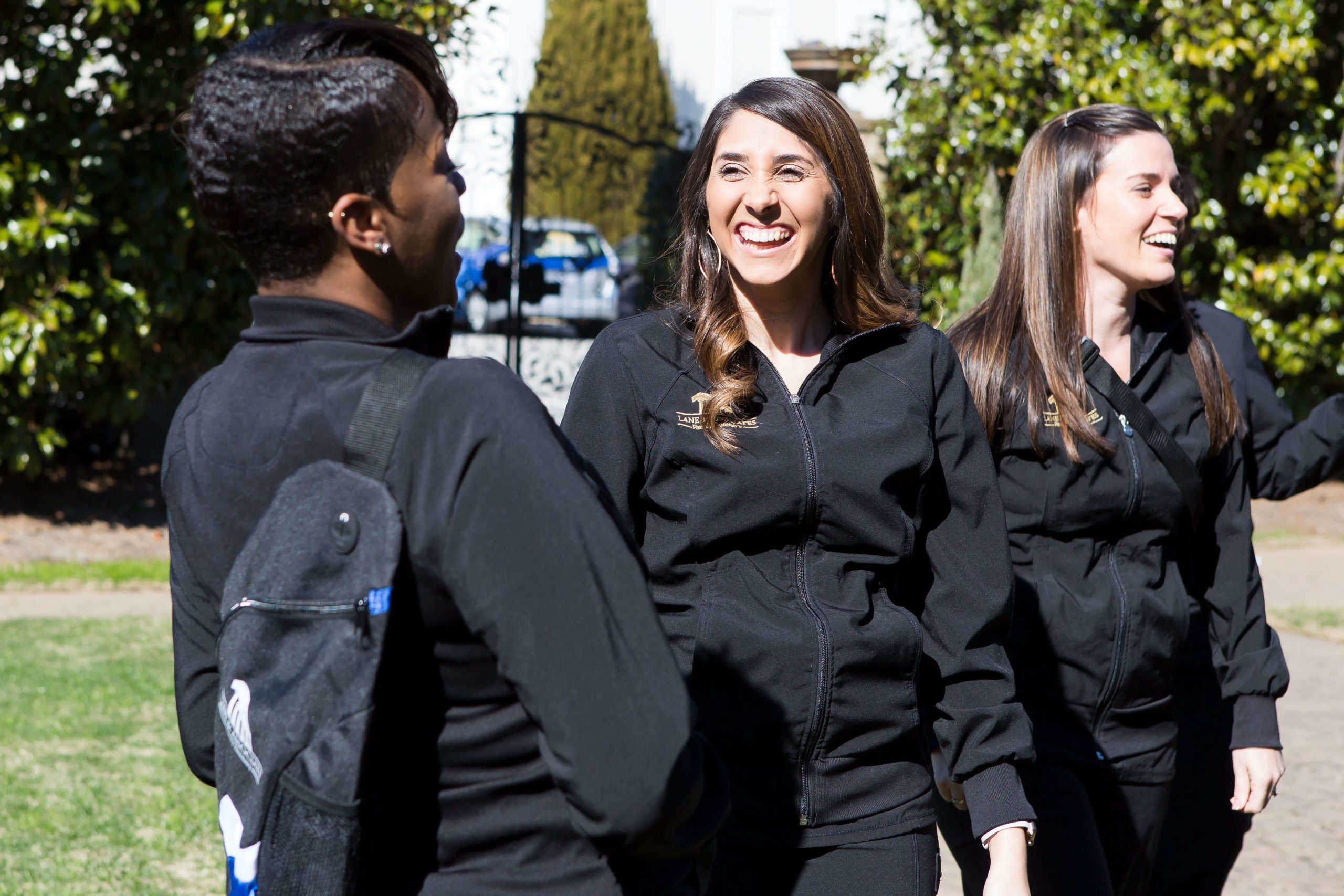 Garner Dentist staff laughing outside of the office wearing Lane and Associates dental scrubs