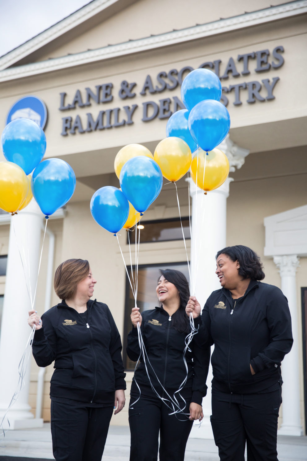 Group of Dental Assistants laughing with yellow and blue balloons in front of dental office in Winston Salem