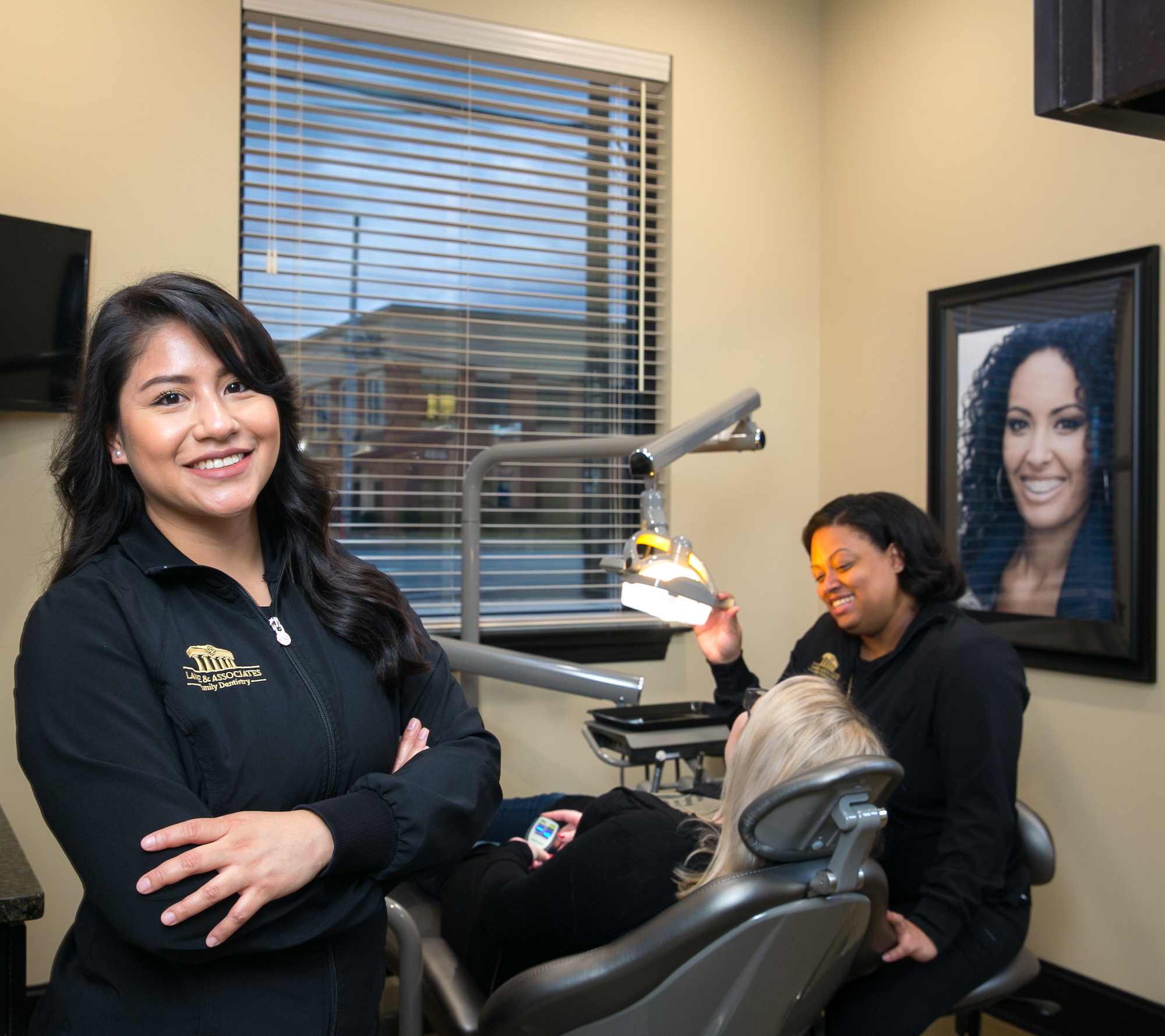 Dental Assistant in foreground with patient and hygienist in background