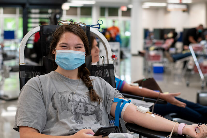 Girl with mask on giving blood