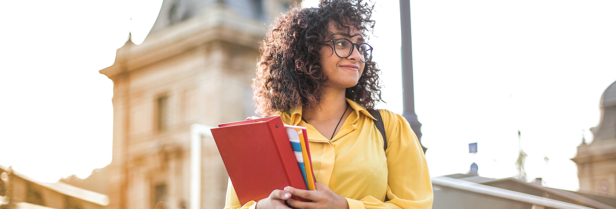female carrying books wearing glasses